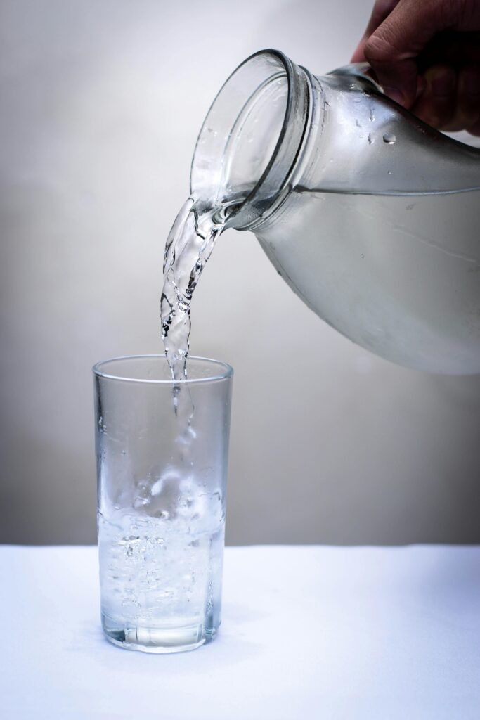Crystal clear water being poured into a glass from a pitcher. Refreshing and hydrating concept.
